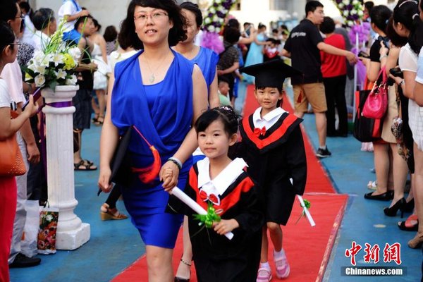 6月28日，山東青島開發(fā)區(qū)第一幼兒園怡和嘉園分園2014級(jí)大班舉行畢業(yè)典禮，全體畢業(yè)生身著學(xué)士服在盛裝父母的陪同下，依次走過紅毯，在畢業(yè)榜上鄭重簽下自己的名字，其氣勢(shì)不輸當(dāng)紅影星紅毯秀。中新社發(fā) 俞方平 攝 圖片來源：CNSPHOTO