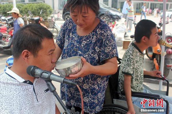 每天起床后便匆匆來到街頭“賣唱”，呂愛梅只能把面湯熬好在小強(qiáng)和小猛唱歌間隙喂他們吃。馬義恒 攝