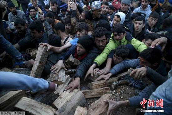 當(dāng)?shù)貢r(shí)間2016年3月6日，希臘Idomeni，滯留希臘與馬其頓邊境的移民蜂擁爭(zhēng)搶木柴。