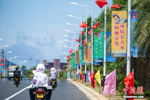 6月24日，海南省文昌市龍樓鎮(zhèn)街道兩側(cè)五星紅旗迎風(fēng)飄揚(yáng)，火箭“首發(fā)”宣傳廣告隨處可見。長征七號(hào)運(yùn)載火箭發(fā)射日期臨近，中國首個(gè)濱海航天發(fā)射中心——文昌航天發(fā)射場(chǎng)所在地海南省文昌市龍樓鎮(zhèn)將迎來“首發(fā)”，中國的“卡納維拉爾角”正揭開神秘面紗。中新社記者 駱云飛 攝