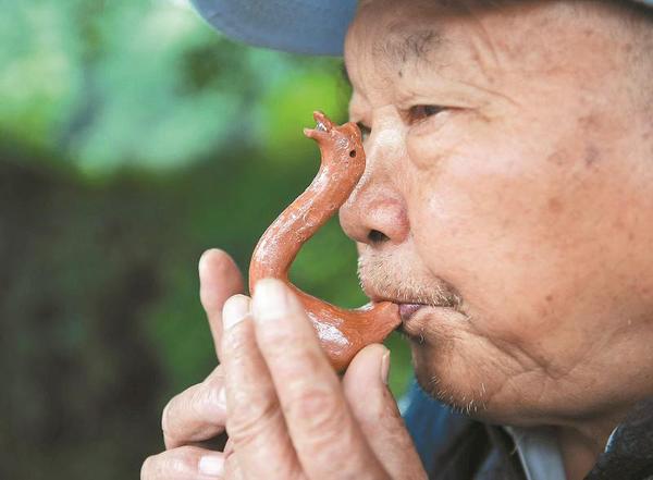 萬富冊老人為過往市民吹奏泥鵝子。