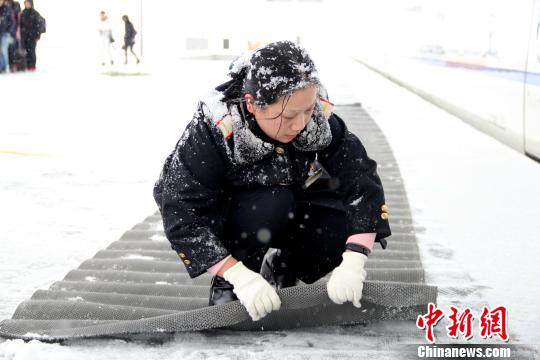 圖為鐵路工作人員在站臺(tái)上鋪設(shè)防滑墊。　秦姝　攝