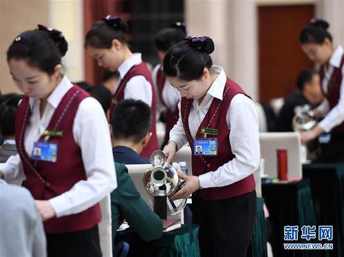 3月6日，北京華北賓館的女服務(wù)員在民盟、無黨派人士界委員聯(lián)組會(huì)上倒水。在兩會(huì)會(huì)場內(nèi)外，女代表、女委員、女工作人員、女記者在工作中盡職盡責(zé)，展現(xiàn)著自己的風(fēng)采。 新華社記者張鐸攝