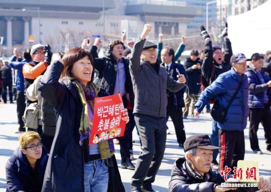 3月10日，在象征著韓國(guó)政治中心的首爾光化門(mén)廣場(chǎng)，民眾在聽(tīng)到憲法法院對(duì)總統(tǒng)樸槿惠彈劾案的審判結(jié)果后歡呼。韓國(guó)憲法法院當(dāng)日作出裁決，宣布彈劾案成立。樸槿惠成為韓國(guó)歷史上首位被彈劾罷免的總統(tǒng)。<a target='_blank' href='http://www.chinanews.com/'>中新社</a>記者 吳旭 攝