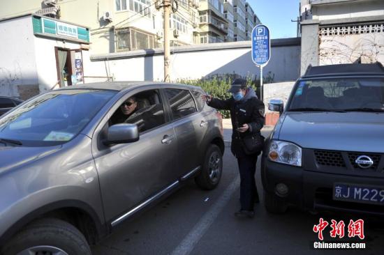 今年元月起，北京全市3000多名路側(cè)停車管理員上崗證更換，新上崗證標(biāo)有二維碼，市民用手機(jī)掃描即可看到管理員的照片、姓名、所在公司、監(jiān)督電話等詳細(xì)信息。若冒用或偽造，掃描出來的信息將與實(shí)際不符，一旦遇到假收費(fèi)員，市民有權(quán)拒絕交費(fèi)。圖為停車場(chǎng)管理員張大姐為車主指揮倒車。<a target='_blank' href='http://www.chinanews.com/' >中新網(wǎng)</a>記者 金碩 攝