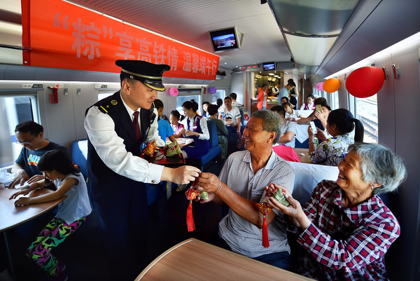 北京鐵路局天津客運段值乘的廈門北至北京南G324次列車長為老年旅客送上粽子與香囊紀念品。