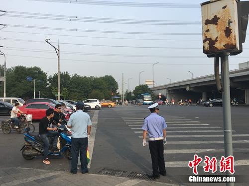 6月21日上午，北京仰山橋下十字路口，執(zhí)勤人員要求非機(jī)動(dòng)車停在停止線后。湯琪 攝