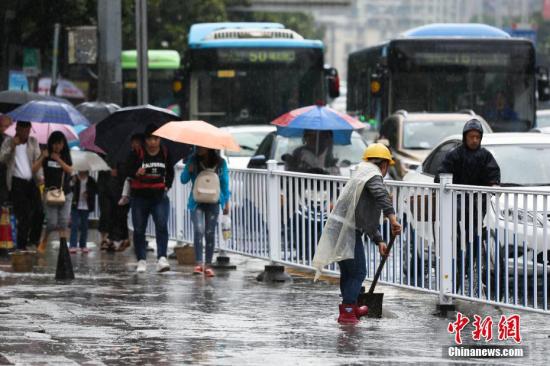 資料圖：行人在雨中出行。 黃芷昕 攝