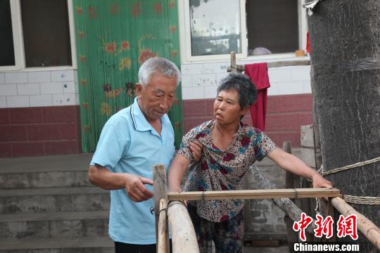 為讓妻子慢慢學會走路，李文生每天扶著妻子一遍一遍練習走路?！±钤杭t 攝