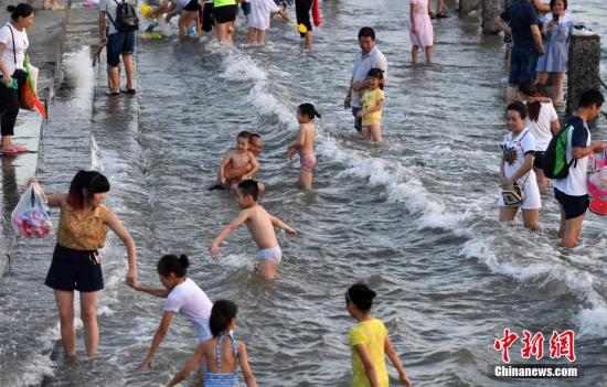 7月4日傍晚，市民們帶著小孩在海邊戲水消暑。連日來，受副熱帶高壓影響廈門地區(qū)持續(xù)高溫。 張斌 攝