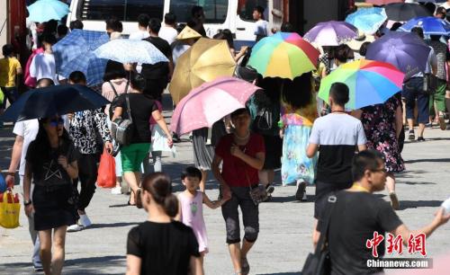 7月12日，廈門一景點(diǎn)游客們紛紛打起傘遮擋烈日。張斌 攝