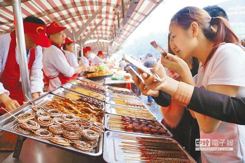 北京一“蟲子宴”攤位，擺滿串蛇、蜈蚣、螞蚱、蜘蛛等，不少食客拿出手機拍照。（臺灣中時電子報）