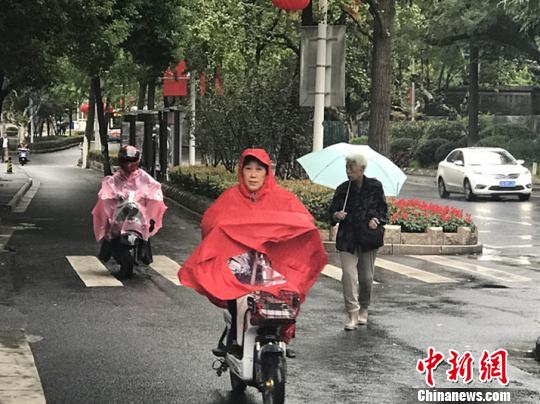 11日，南京迎來降溫降雨。圖為市民披上雨衣出行?！铑伌?攝