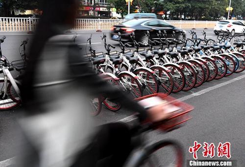 資料圖：路人騎著共享單車經(jīng)過“車堆”。<a target='_blank' href='http://www.chinanews.com/'>中新社</a>記者 張斌 攝