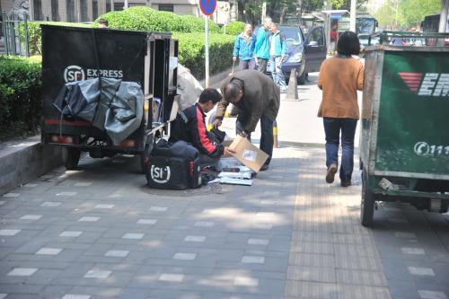 圖為快遞小哥在路邊配送快遞。呂春榮 攝