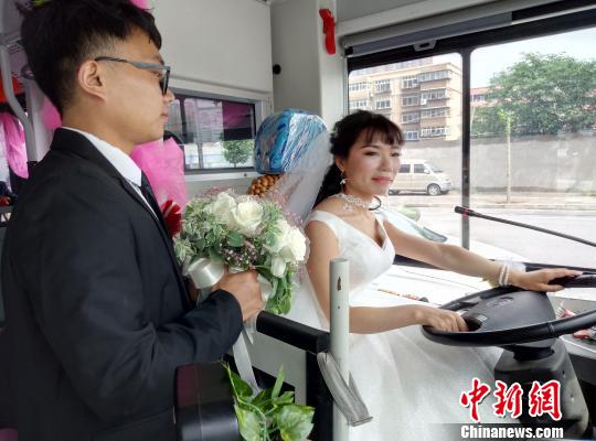 李金可駕駛公交車行駛，丈夫手捧鮮花守護在側(cè)?！≈煨?攝