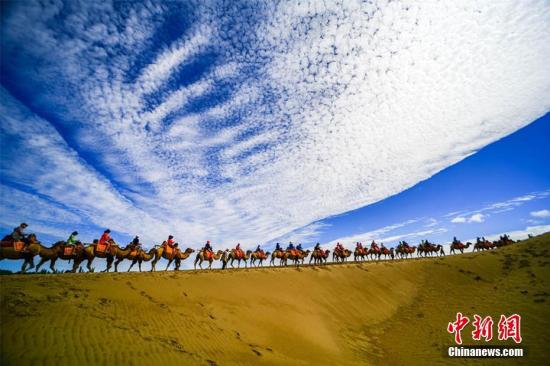 資料圖：甘肅敦煌鳴沙山月牙泉景區(qū)藍(lán)天、白云、黃沙相映成趣，每天吸引數(shù)萬中外游客觀光游覽。 王斌銀 攝