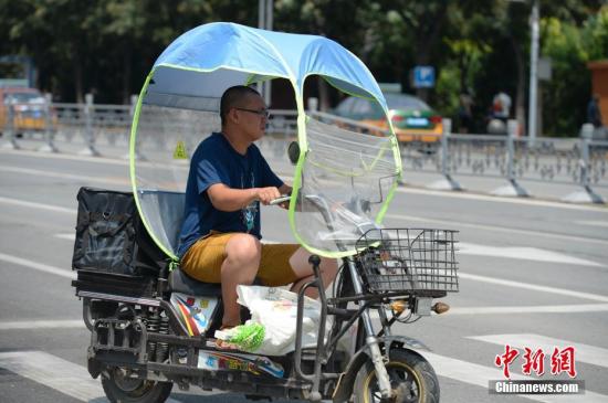 資料圖：男子在電動車上撐起遮陽棚。<a target='_blank' href='http://www.chinanews.com/'>中新社</a>記者 劉文華 攝