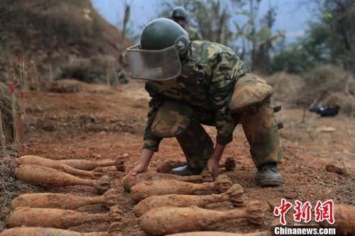 中國人民解放軍南部戰(zhàn)區(qū)陸軍云南掃雷大隊在雷場掃雷期間，一名戰(zhàn)士將一枚搜排出來的炮彈放至臨時存放點?！蠲?攝