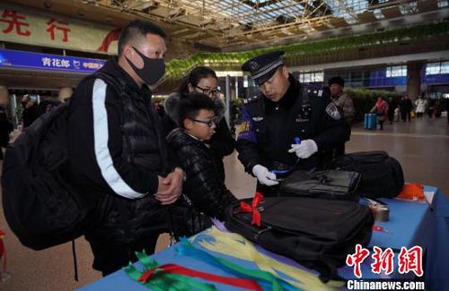 12月28日，北京西站派出所民警為背黑色雙肩包的旅客系上個(gè)性小標(biāo)識(shí)，以防在通過(guò)安檢或乘車(chē)過(guò)程中出現(xiàn)錯(cuò)拿情況。(完) 龐賀雷 攝