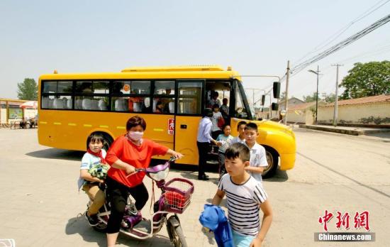 資料圖：學(xué)生家長接送從校車上下來的學(xué)生。 張道正 攝