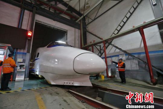 一列動車組駛?cè)胲噹?，機械師位列兩邊檢查車體外觀?！《〔?攝