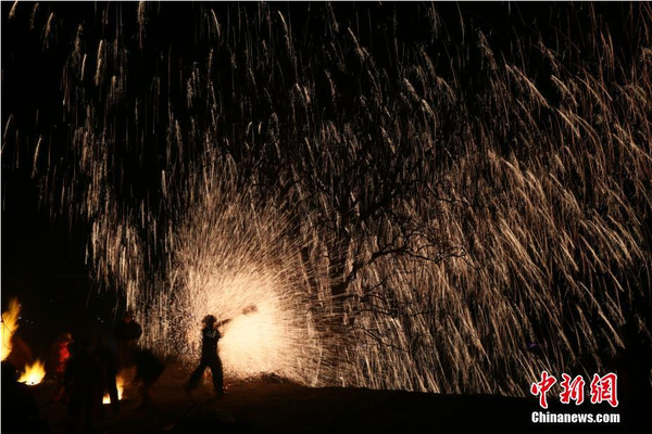 該村“打樹花”的習(xí)俗已延續(xù)了近600年，村民將生鐵融成鐵水后，再用特制的木板將鐵水擊打至樹上，頓時(shí)綻放出萬點(diǎn)“鐵花”。中新社記者 陳昊 攝