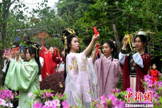 福建漢服少女將將寫(xiě)有對(duì)春日祝福的彩帶系在百花枝頭，共同送上美好的祝愿?！蚊?攝