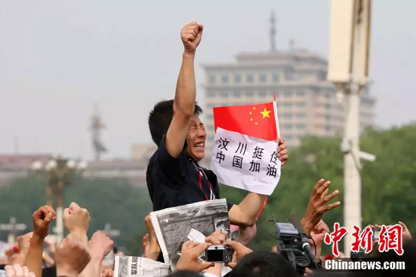 2008年5月19日，北京天安門廣場(chǎng)上的民眾為地震遇難者默哀，一位來(lái)自四川的男子高舉右手為家鄉(xiāng)加油。中新社記者 富田 攝