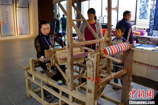 非遺傳承人向觀眾展示織布機(jī)的使用方法。　張強(qiáng) 攝